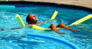 Child in water laying on back relaxing on noodles